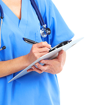 Nurse in blue scrubs writing on a clipboard